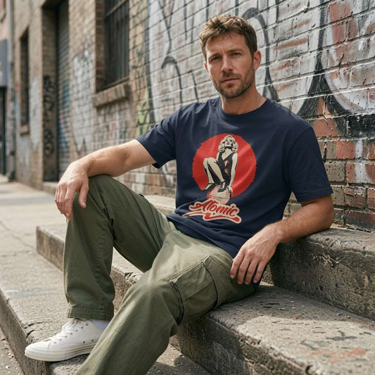 Man in navy Atomic pin-up graphic t-shirt sat on graffiti steps, cool mens music shirt