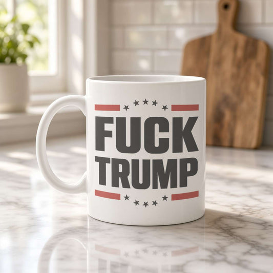 A white ceramic mug on a marble kitchen counter reads “FUCK TRUMP” in bold lettering with red stripes and stars; the bright kitchen feels calm and homey.