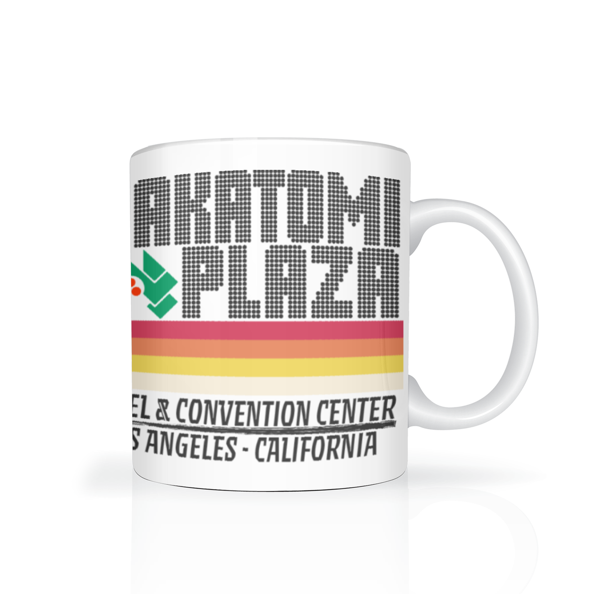 A white ceramic mug displays a retro “Akatori Plaza” design with a green emblem, colored stripes, and Los Angeles convention center text; clean, nostalgic look.