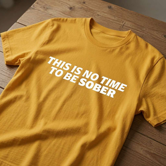 Mustard yellow t-shirt laid flat on a wooden table with the bold white slogan “This Is No Time To Be Sober”, classic sarcastic drinking banter design