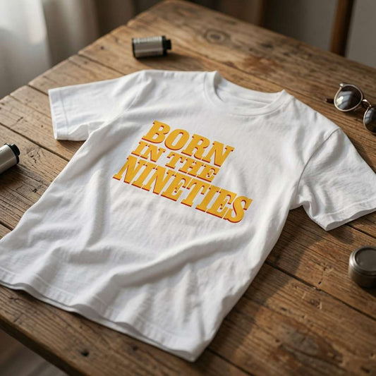White Born in the Nineties t-shirt laid flat on a wooden surface with bold yellow lettering, ladies 90s film inspired born in slogan shirt