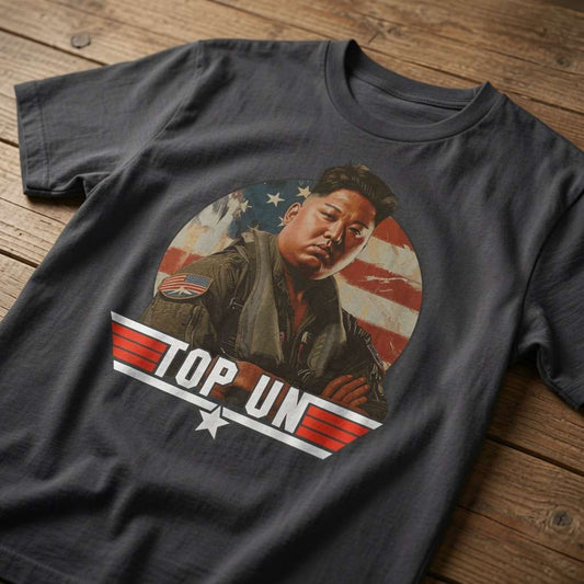 Black Top Un t-shirt laid flat on a wooden surface showing the full Kim Jong Un Top Gun parody graphic, funny and witty satire design