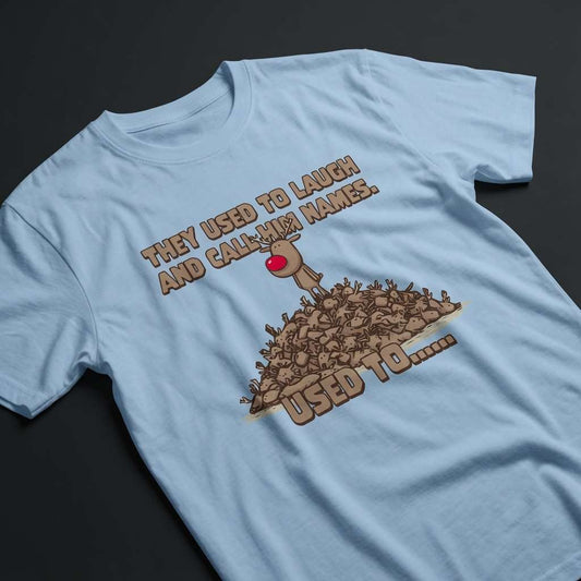 Light blue They Used to Laugh and Call Him Names t-shirt laid flat showing the full Rudolph and antler pile graphic, funny dark humor Christmas reindeer design that every cheeky lad will claim