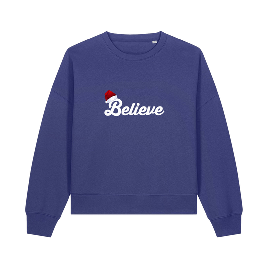 blue christmas sweater with the slogan 'believe' and a santa hat on top of the b