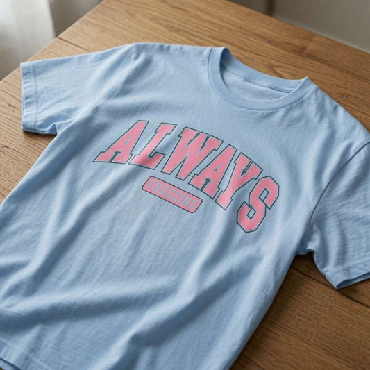 Light blue Always Freezing t-shirt on wood with pink collegiate text, ladies relatable funny