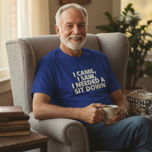 Man sitting in a chair wearing a blue t-shirt with humorous text, holding a mug.