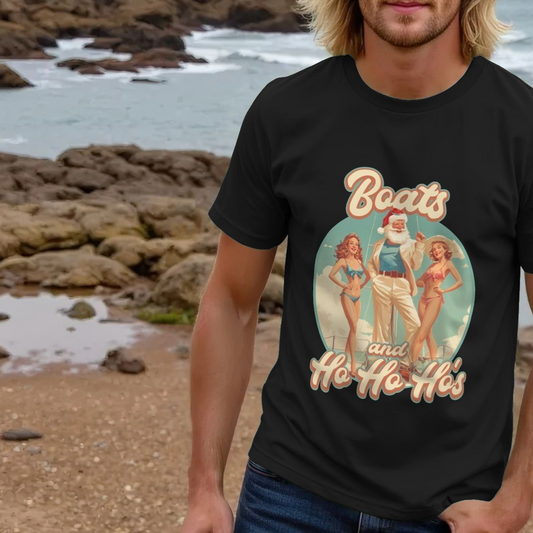 A person wearing a Funny Christmas T-shirt with a retro-style graphic of Santa Claus and two women in swimsuits and the slogan Boats and Ho Ho Ho's, Background shows a rocky coastline.