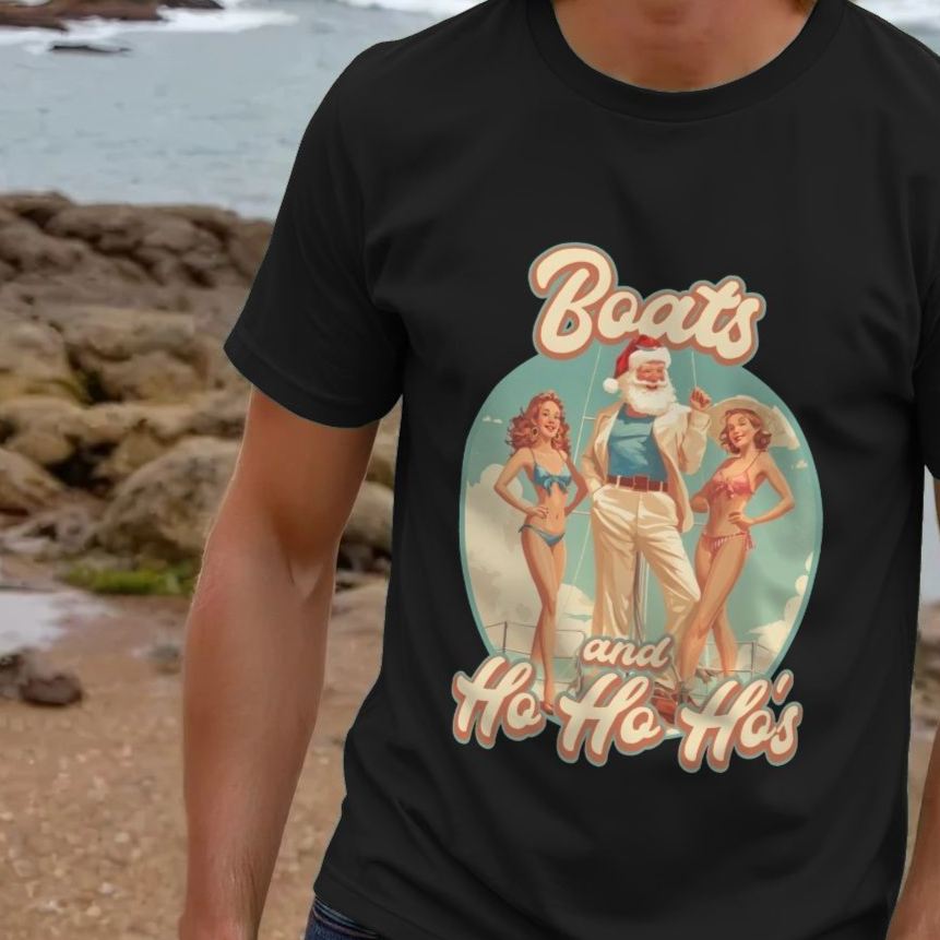 Man wearing a black funny Christmas t shirt with a retro-style graphic of Santa between two women in bikinis, reading "Boats and Ho Ho Ho's." Beach background visible.