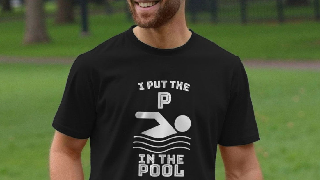 Man in a park wearing a black funny slogan t-shirt with playful text: "I put the P in the pool," featuring a swimming icon. He is smiling, creating a lighthearted mood.