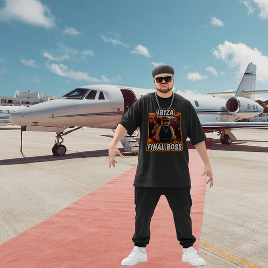 A mountain of a man stands confidently on a red carpet in front of a private jet. He's wearing sunglasses, a black "Ibiza Final Boss" t-shirt, and a chain necklace. The sky is clear and blue.