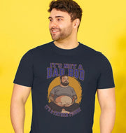 Smiling man in a navy T-shirt with text and image of a bearded figure with tattoos, reading: 