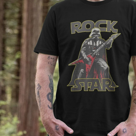 A person stands in a forest, wearing a black t-shirt featuring an illustration of a sci-fi character playing a red electric guitar, with the words "Rock Star" above and below.