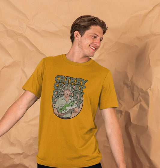 A smiling man in a mustard t-shirt stands against a beige, crumpled paper background. The shirt features Steve Irwin with the text "CRIKEY" repeated.