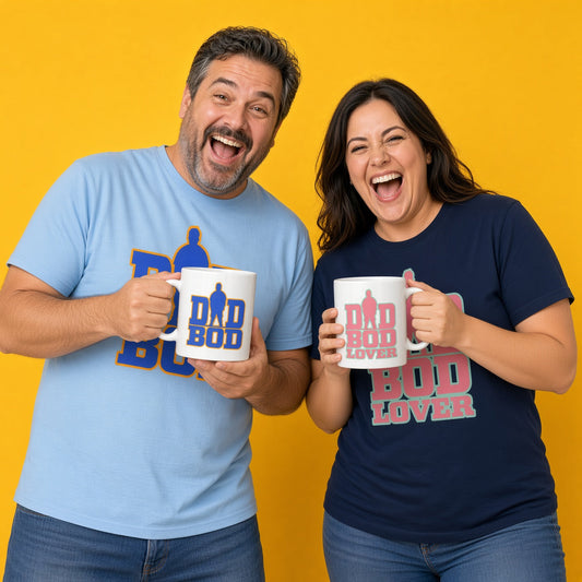 A laughing man and woman standing together against a solid yellow background, wearing matching light blue and navy blue t-shirts while holding white mugs with matching graphics and text that read "DAD BOD" and "DAD BOD LOVER"