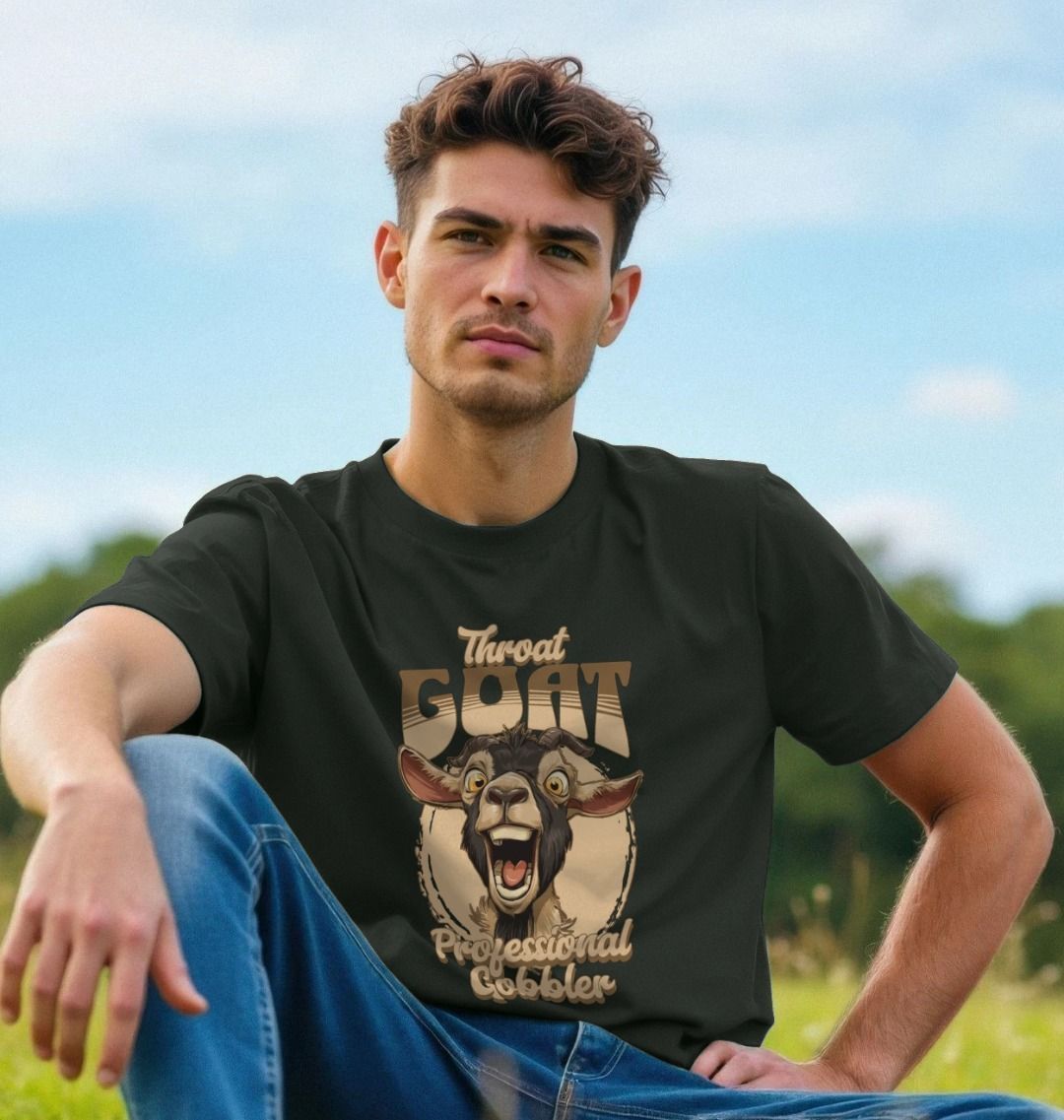 A man sitting outdoors in a field, wearing a black t-shirt with an illustration of a goat and the words "Throat GOAT Professional Gobbler." The mood is casual and relaxed.