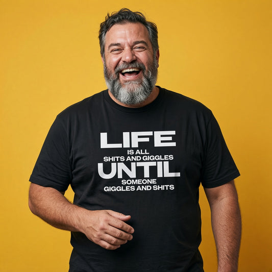 Man laughing while wearing a black Life Is All Shits And Giggles Until Someone Giggles And Shits t-shirt, funny mens witty relatable slogan design full of pure attitude