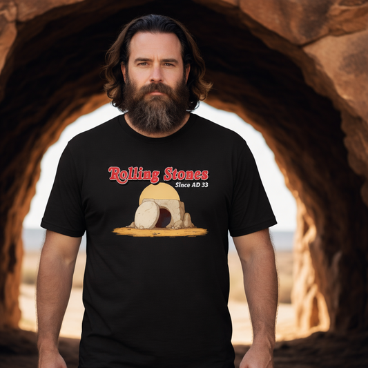 man wearing a navy t-shirt with the graphic of a boulder in front of a cave and the slogan 'rolling stones since AD33'