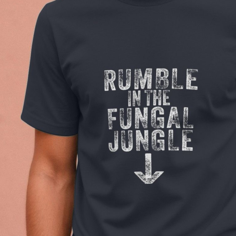 A person wearing a dark offensive T-shirt with distressed white text reading "Rumble in the Fungal Jungle" and a downward arrow. The mood is casual and playful.
