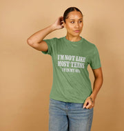A person with tied-back hair poses in a green T-shirt, reading 
