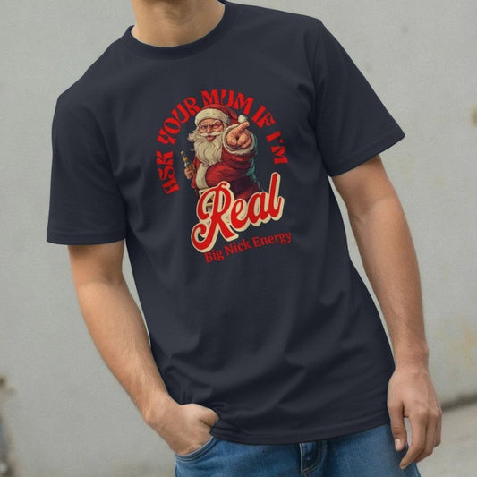 Man wearing a black T-shirt with a playful Santa design, featuring the text "Ask your mum if I'm real" and "Big Nick Energy," exuding humour and holiday cheer.