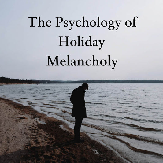 Person walking alone by the water during winter, illustrating an article on the psychology of seasonal blues and holiday melancholy.