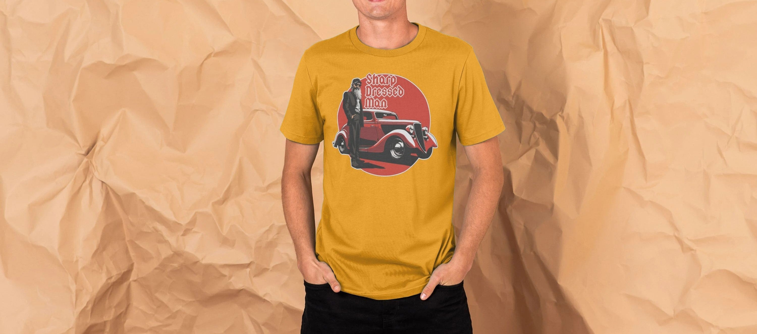 Man in a yellow Music t-shirt with a graphic of a vintage hot rod car and a person, labeled "Sharp Dressed Man," standing against a crumpled paper background.