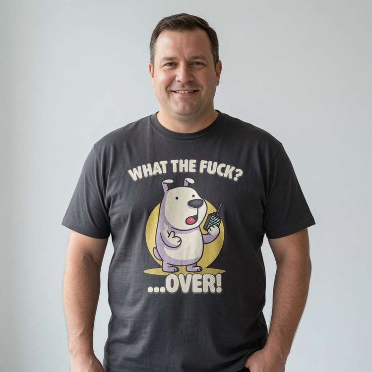 Man smiling with both hands in his pockets while wearing a black What the Fuck? …Over! t-shirt, funny rude phonetic alphabet pup mens shirt full of pure attitude