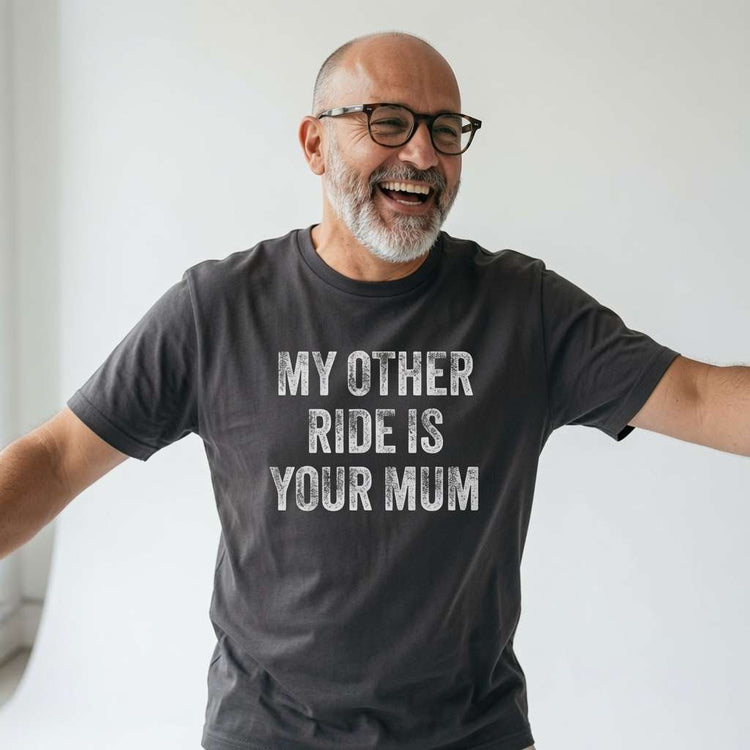 Bald man with glasses laughing with arms outstretched in a black My Other Ride Is Your Mum t-shirt, cheeky and funny dad slogan that always gets a reaction