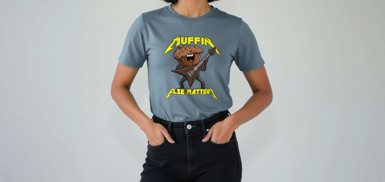 A Woman wearing a blue Music T-shirt with a cartoon muffin playing an electric guitar. The words "Muffin Else Matters" are printed in a Metallica inspired font, bold, yellow letters.