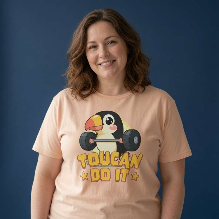 Woman smiling in a peach Toucan Do It t-shirt, cheeky pun and motivational bird design that every no-nonsense lady will claim