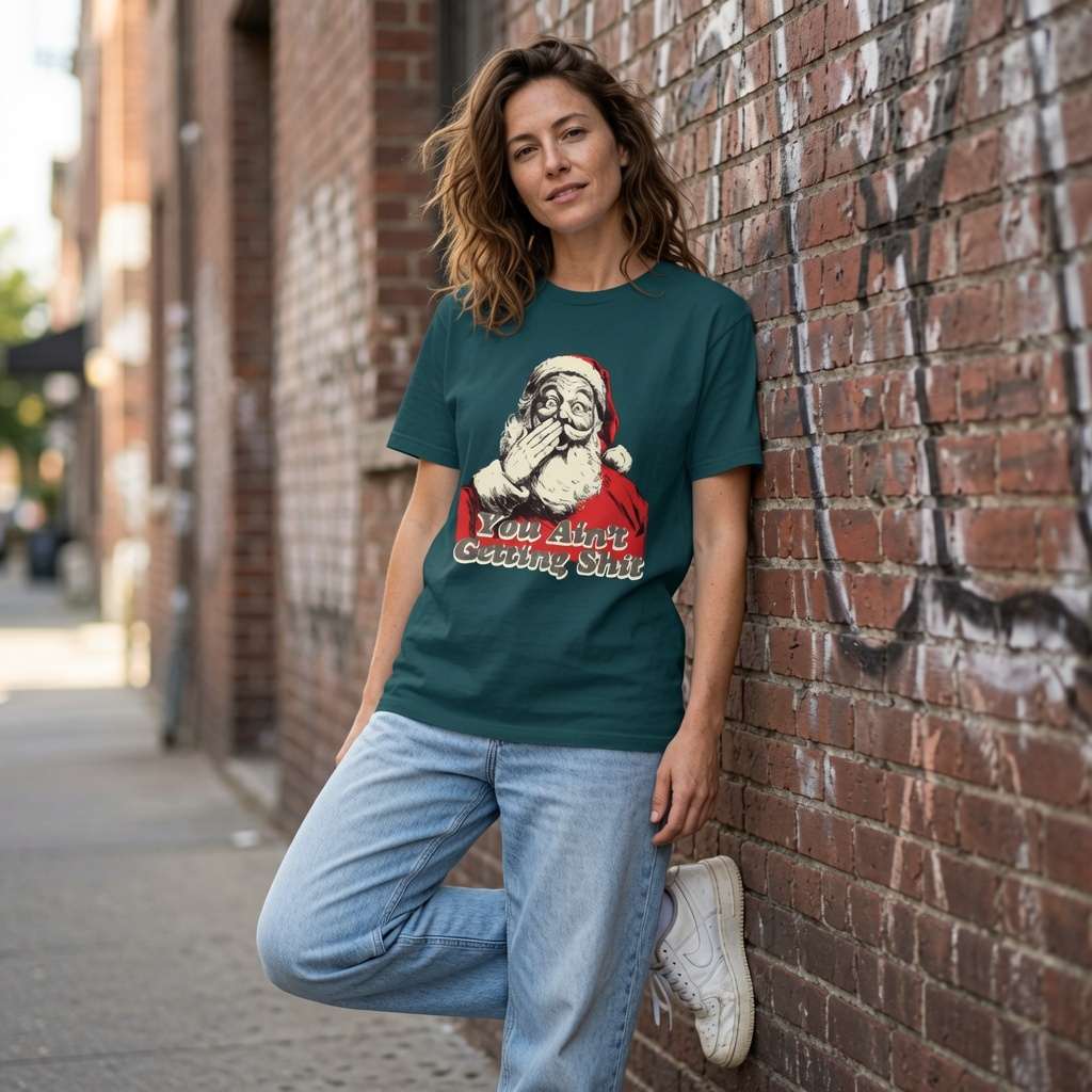 Woman in green You Ain’t Getting Shit Santa tee leaning on brick wall, fun ladies xmas gift