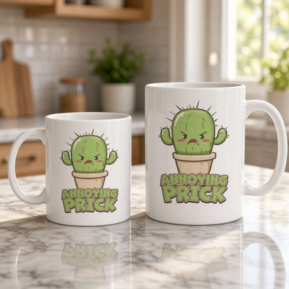Two white mugs of different sizes on a bright kitchen counter feature an angry cartoon cactus and the words “Annoying Prick,” creating a cheeky, humorous tone.