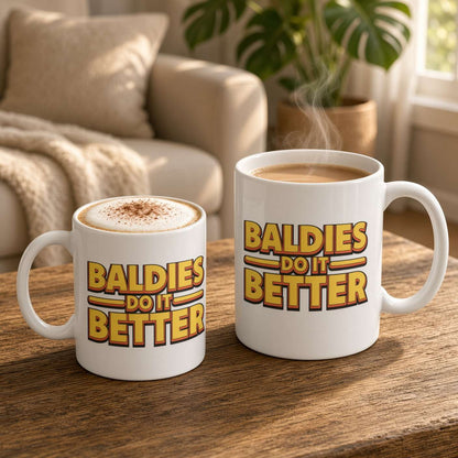 Two white mugs on a wooden coffee table read “Baldies Do It Better”; one holds cappuccino dusted with cocoa, the other steaming coffee, in a cozy, sunlit living room.