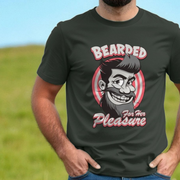 Person wearing a black funny graphic t-shirt with a cool graphic design of a bearded man and the slogan 'Bearded For Her Pleasure' against a blurred green and blue background.