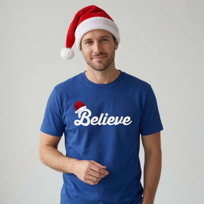 Man in blue Believe t-shirt wearing Santa hat, mens fun santa hat christmas text tee