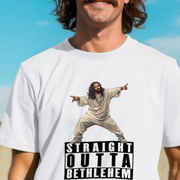 Person wearing a white funny offensive t-shirt with a hip hop graphic of Jesus in a robe and 'Straight Outta Bethlehem' slogan against a blue sky.