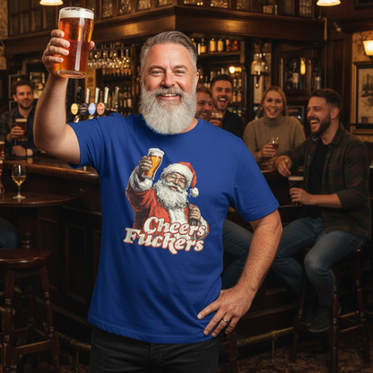 Man in a bar wearing a blue Rude Christmas t-shirt with a graphic of Santa Claus holding a beer and text, holding a beer.