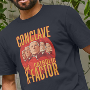 Person wearing a funny graphic t-shirt with the slogan 'Conclave The Catholic X-Factor' design.