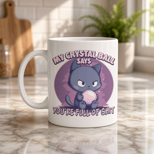 A white mug on a sunlit marble kitchen counter features a grumpy purple cat holding a crystal ball and the joke, “My crystal ball says you’re full of shit.”