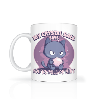 A white mug features a grumpy purple cat holding a glowing crystal ball, with the humorous text, “My crystal ball says you’re full of shit.”