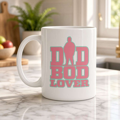 A white ceramic coffee mug with a pink and teal graphic reading 'DID BOD LOVER' sits on a marble kitchen countertop with a blurred kitchen background.