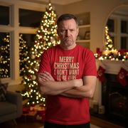 Man wearing a red Christmas slogan shirt with a Christmas message in a decorated living room.