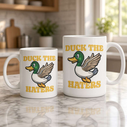 Two white ceramic mugs on a marble kitchen counter feature a cartoon duck and the phrase “Duck the Haters,” creating a playful, upbeat mood.