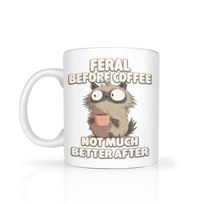A white mug displays a wide-eyed, scruffy cartoon cat sipping coffee, with the caption “Feral before coffee, not much better after”—a playful, sleepy morning joke.