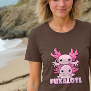 A smiling woman stands on a beach wearing a brown Novelty T-Shirt with two cute pink cartoon axolotl design and the word 