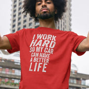 Young man poses confidently outdoors, wearing a red car slogan T-shirt with the humorous text, 