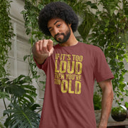 A man with curly hair winks and points playfully, wearing a brown Funny Slogan T-shirt reading, 