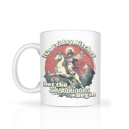 A white ceramic mug with a humorous graphic print of Jesus riding a unicorn, set against a red circular background with the text 'It's Friday Bitches Let the Shenangans Begin'.
