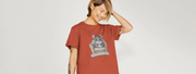 Smiling Woman with short hair wears a rust-colored cute Animal T-shirt featuring a relaxed cartoon chinchilla with the words 