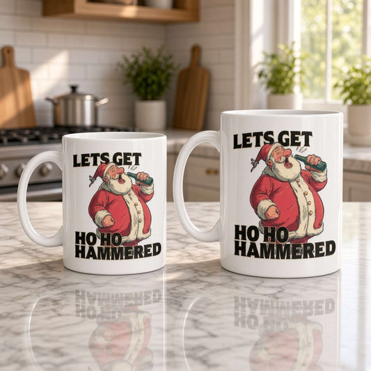 Two white ceramic mugs with a humorous Santa graphic and the text 'LETS GET HO HO HAMMERED' are displayed on a marble kitchen counter.